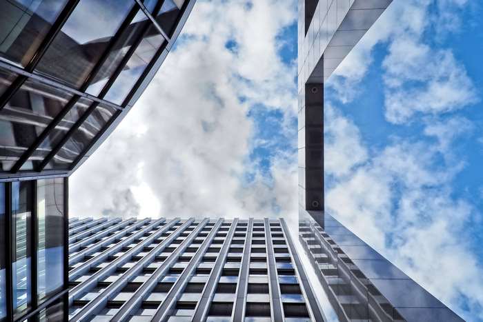 Modern architecture with glass facade against blue sky with clouds 4K
