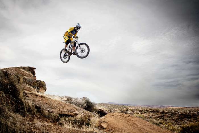Mountain biker jumps over a rocky desert landscape