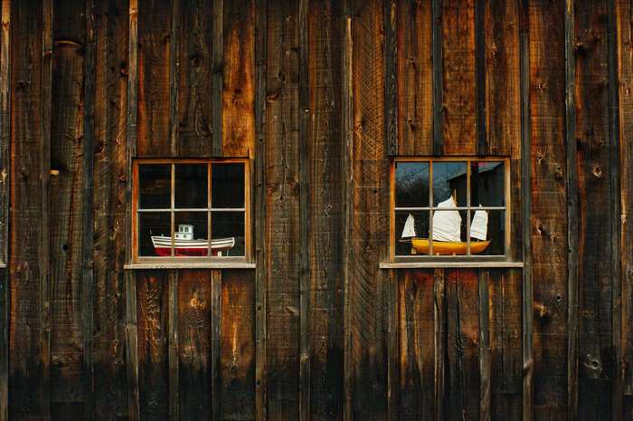 Two windows with model boats on a wooden wall