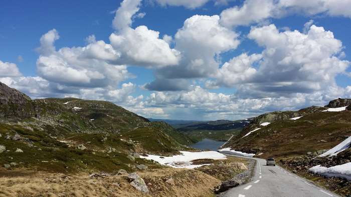 Road through mountains in Norway with lake and clouds