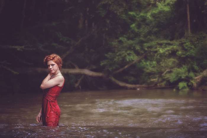 Woman in red dress standing in a river
