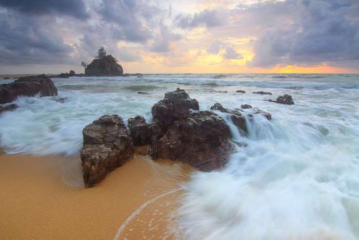 Waves crashing on rocky shore at sunrise