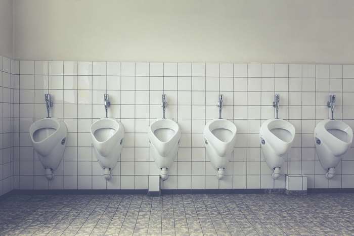 Row of white ceramic urinals on a tiled wall