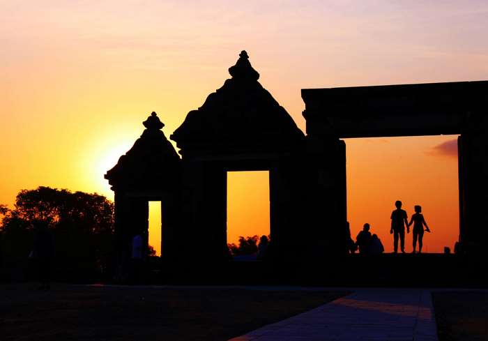 Couple silhouetted against sunset at Ratu Boko Temple, Indonesia