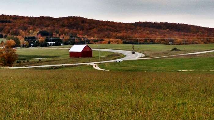Autumn farm scene with red barn and winding road