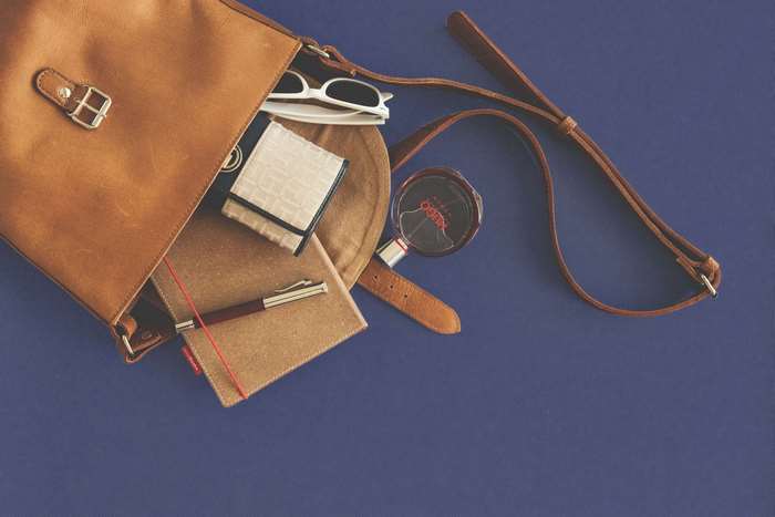 Leather bag with notebook, pen, wallet, sunglasses, and perfume
