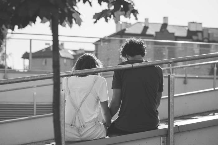 Couple holding hands sitting on a ledge