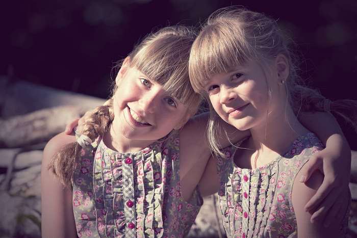Two young girls with braided hair smiling