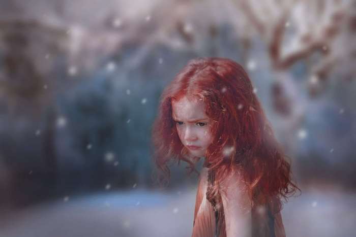 A sad red-haired girl in the snow