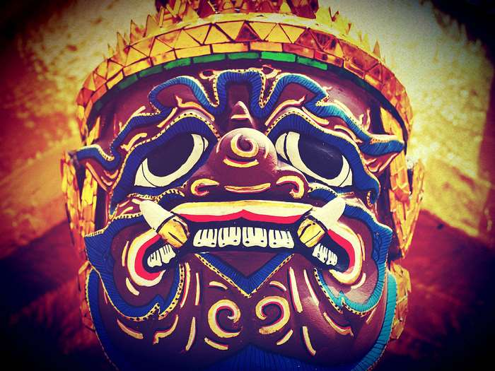 Close-up of a colorful Thai demon mask with golden headdress