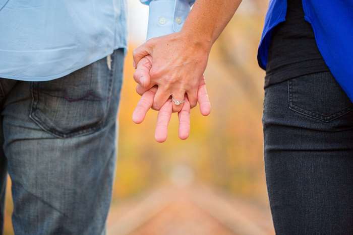 Couple holding hands with engagement ring