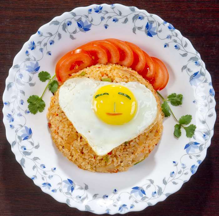 Fried rice with a smiling fried egg and tomatoes