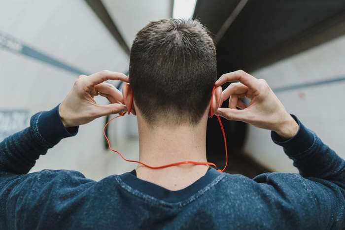 Man putting on red earphones in subway tunnel