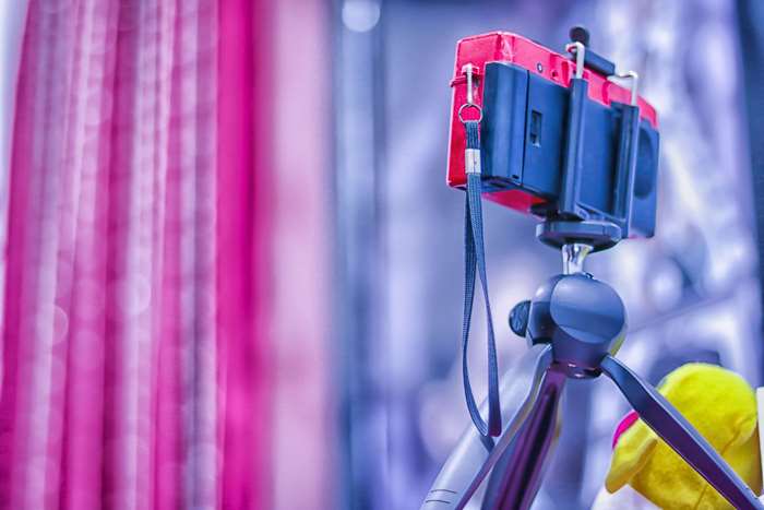 Camera on a tripod with pink curtains