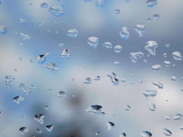 Raindrops on glass with blue sky background 4K