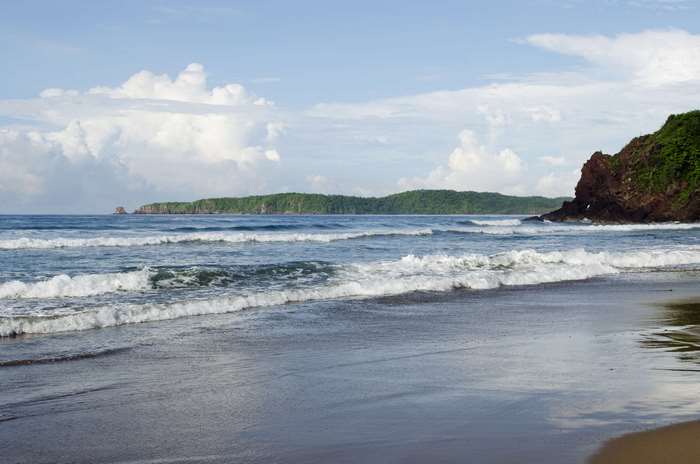 Beach with waves and mountains in the background