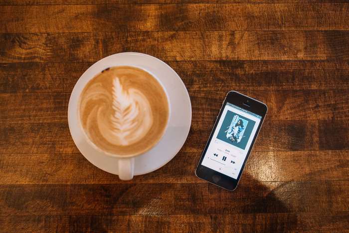 Latte art coffee and iPhone playing music