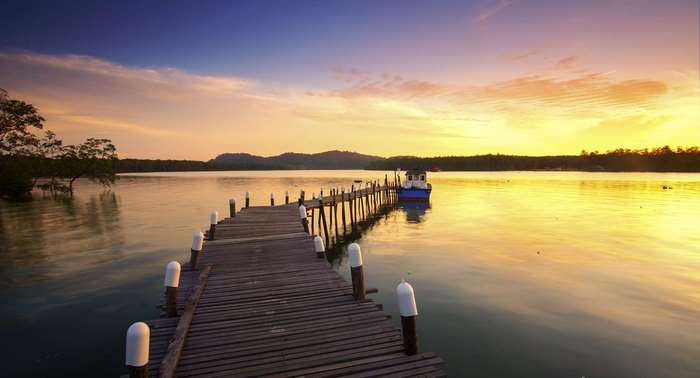 Wooden pier and boat at sunset on a calm lake