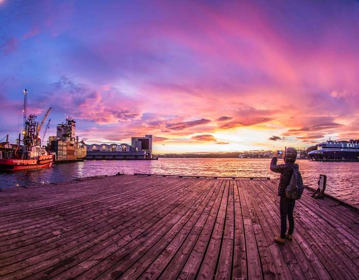 Person photographing a colorful sunset over a harbor in Kristiansand, Norway 4K