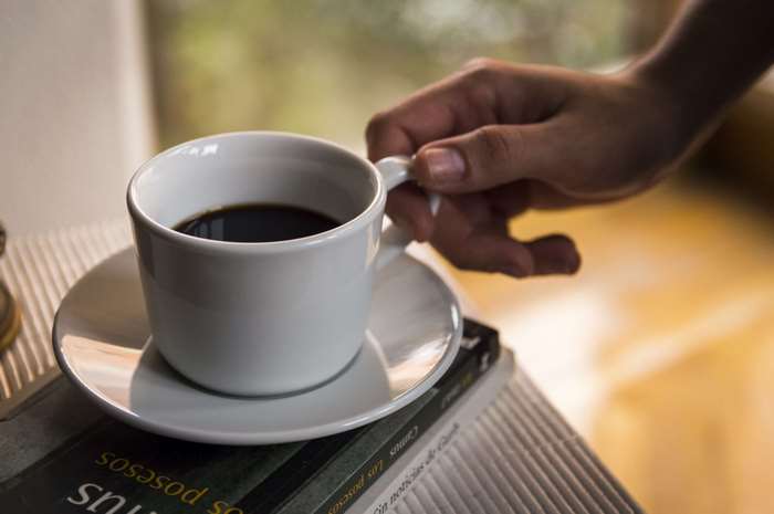 Hand holding a coffee mug over a book