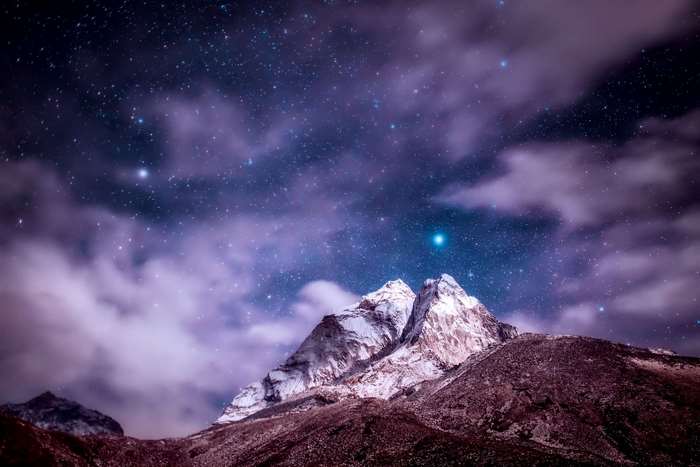 Snow-capped mountains under a starry night sky