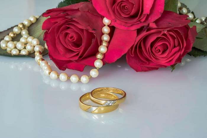 Wedding rings and pearls with red roses