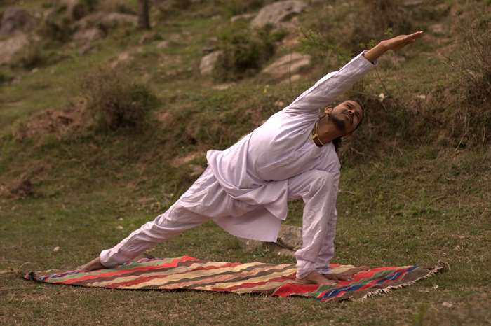 Man in white performing yoga outdoors