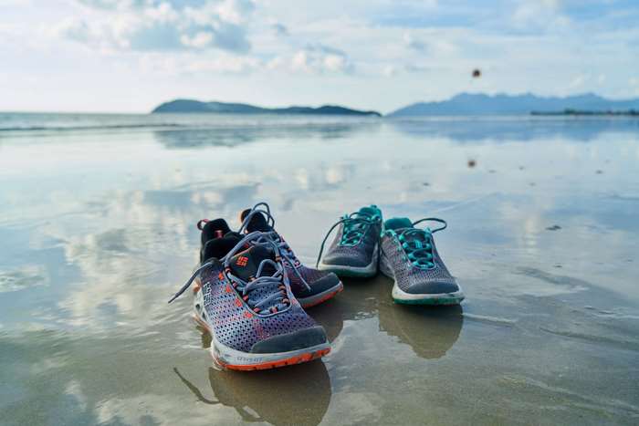 Two pairs of running shoes on a wet beach