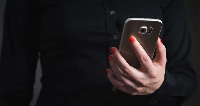 Woman in black shirt holding a smartphone