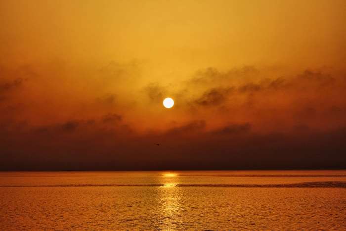 Sunset over the ocean with clouds and reflection