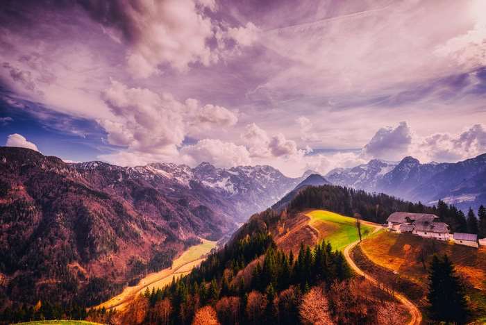 Mountain valley with houses and trees at sunset