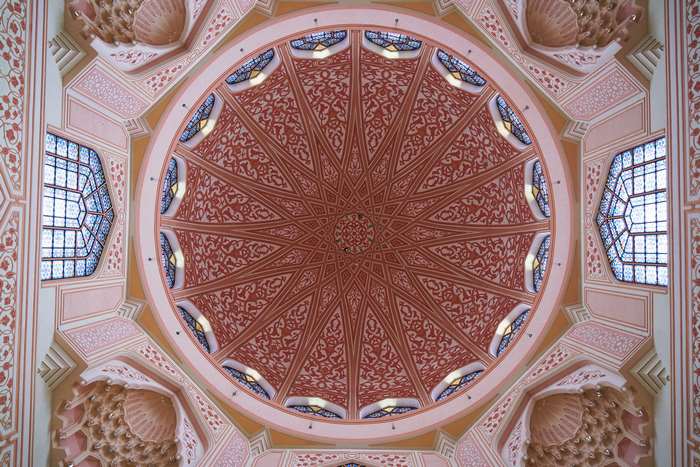 Interior of a mosque dome with intricate patterns and stained glass windows