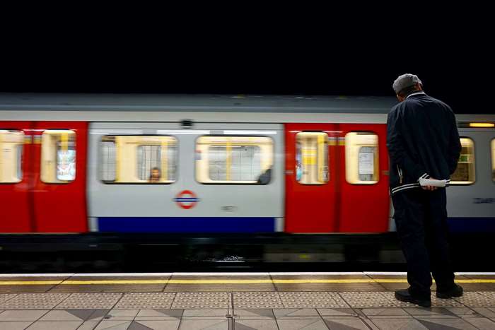 Man on London Underground platform with moving train