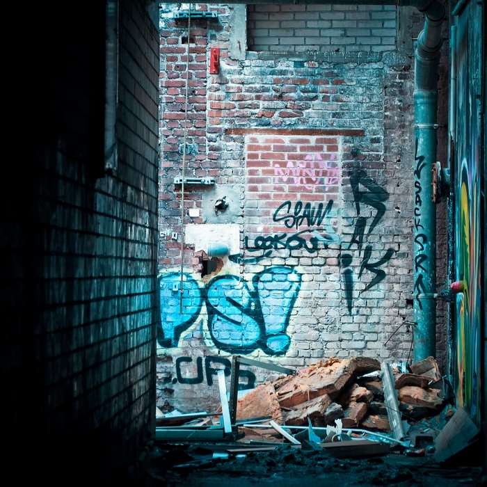 Graffiti on a dilapidated brick wall in an abandoned alley