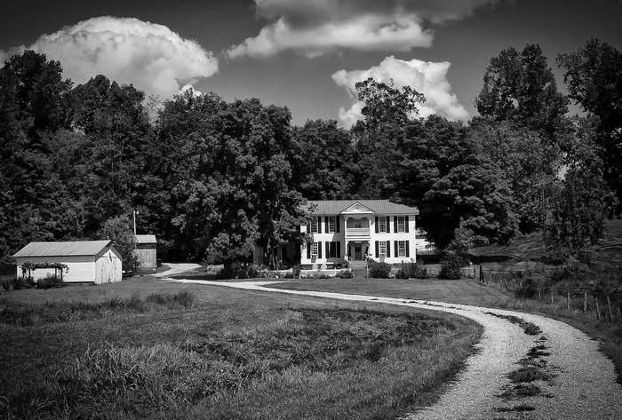 Black and white landscape of a rural manor with a gravel road