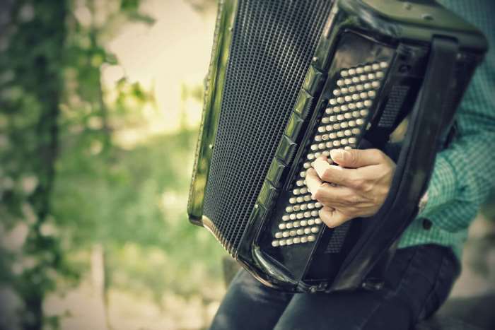 Person playing a black accordion outdoors