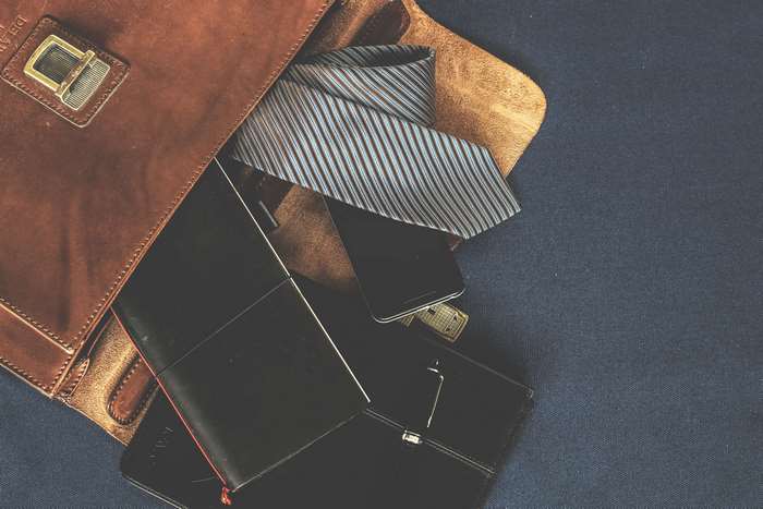 Leather bag with tie, notebook, and phone