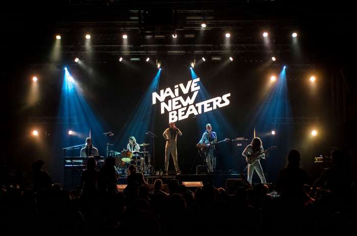 Naive New Beaters band performing on stage with lights