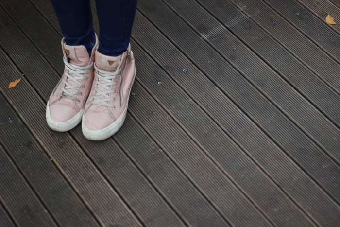Person wearing pink high-top sneakers on a wooden deck