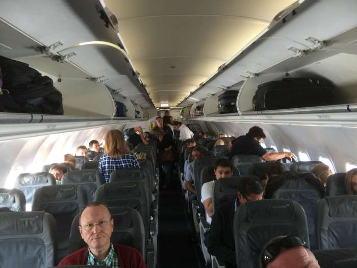 Inside an airplane cabin with passengers and luggage