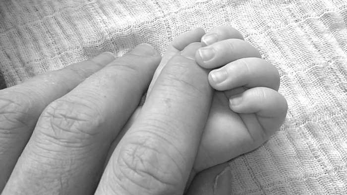 Baby holding adult finger