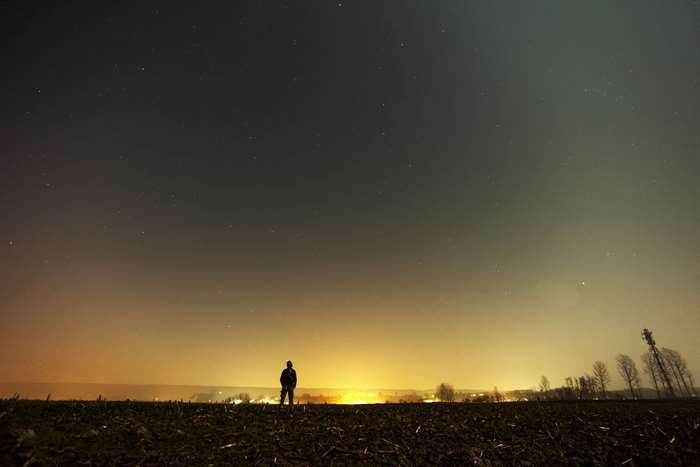 Man standing in a field under a starry night sky