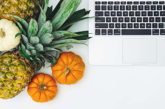 Pineapples and pumpkins next to a laptop