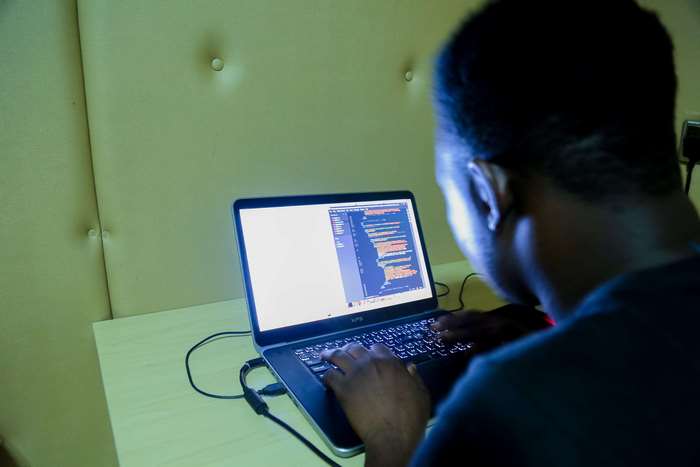 Programmer typing code on a laptop in a studio