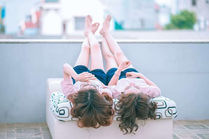 Two women lying on a couch with legs up