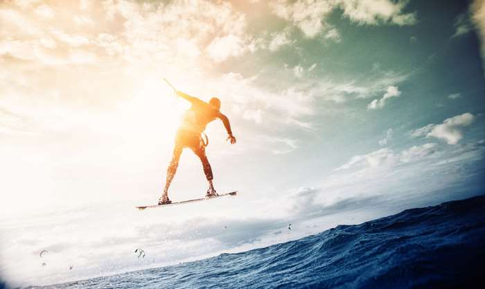Man kitesurfing and jumping over ocean waves at sunset 4K