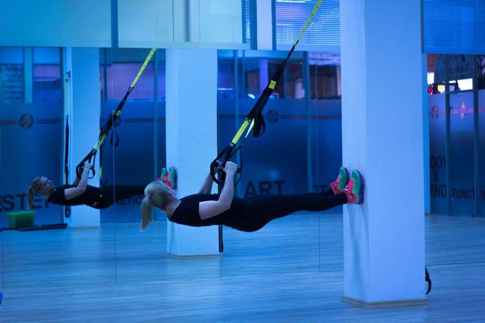 Woman exercising with TRX suspension trainer in gym