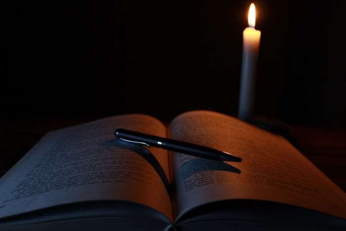 Open book and pen by candlelight 4K