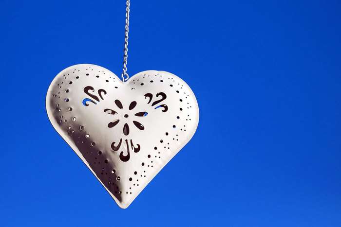 White heart pendant hanging against blue sky