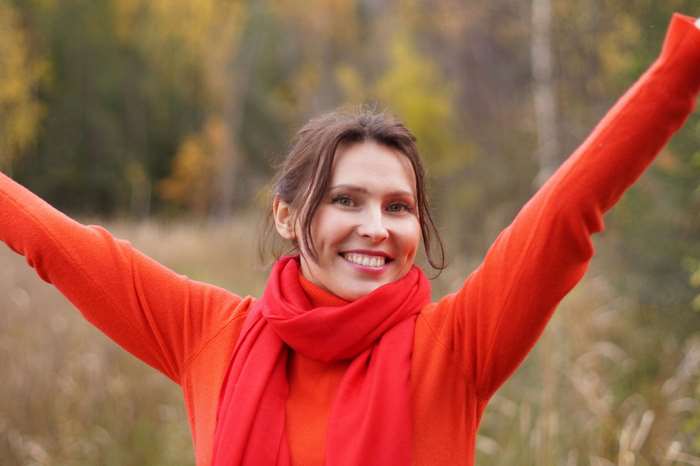 Woman in red sweater and scarf with arms raised